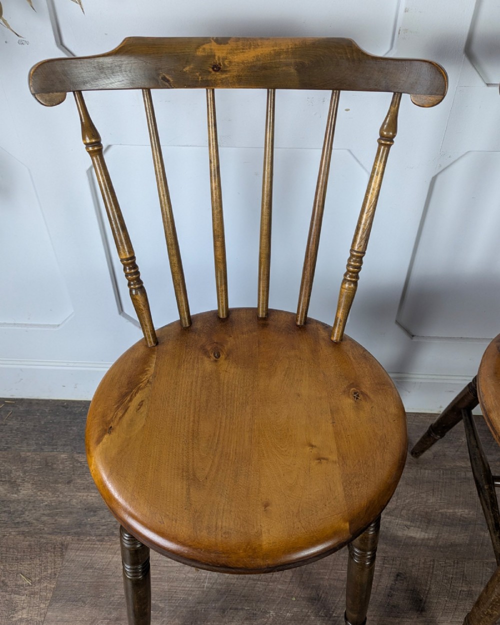 A pair of early twentieth-century wooden Dinco penny chairs featuring spindle backs, turned legs, curved stretchers, and shaped seats. View IX