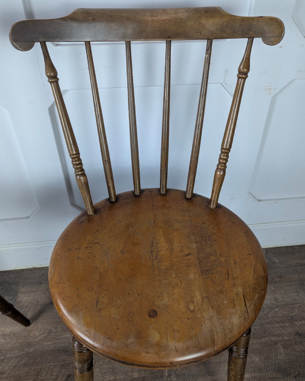 A pair of early twentieth-century wooden Dinco penny chairs featuring spindle backs, turned legs, curved stretchers, and shaped seats. View XI