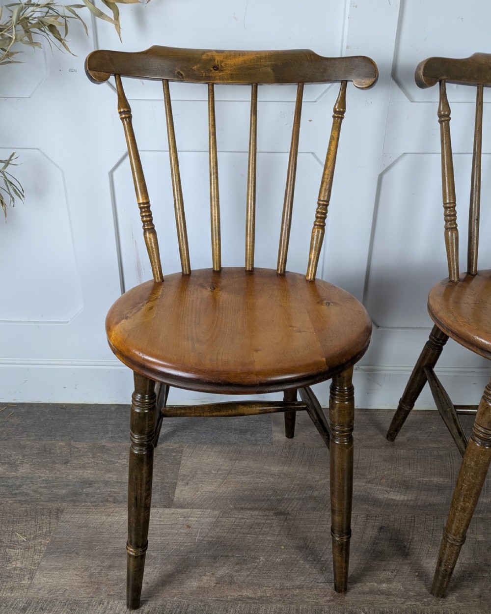 A pair of early twentieth-century wooden Dinco penny chairs featuring spindle backs, turned legs, curved stretchers, and shaped seats. View XII