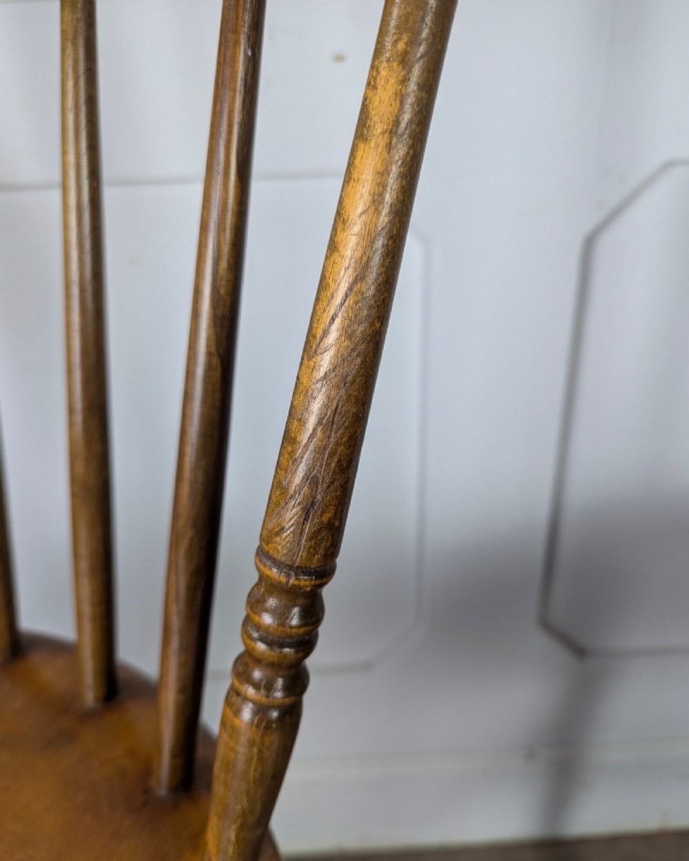 A pair of early twentieth-century wooden Dinco penny chairs featuring spindle backs, turned legs, curved stretchers, and shaped seats. View XIII