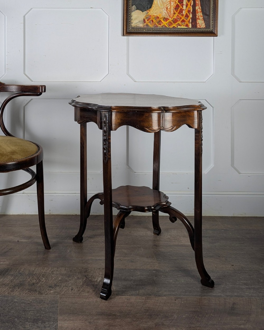 An early 20th-century walnut side table featuring a scalloped rim, carved legs, and a lower undertier shelf.
