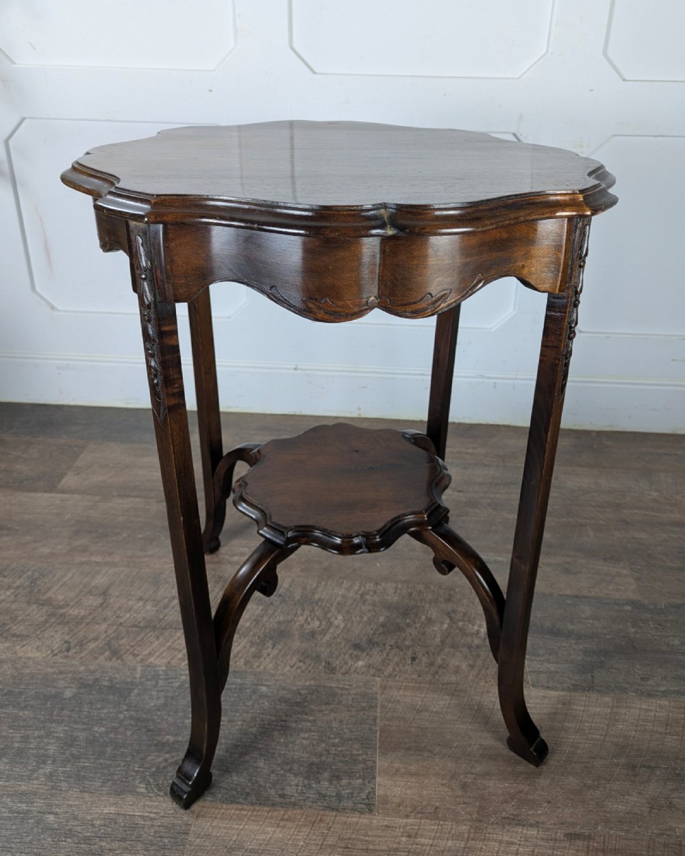 An early 20th-century walnut side table featuring a scalloped rim, carved legs, and a lower undertier shelf. View V