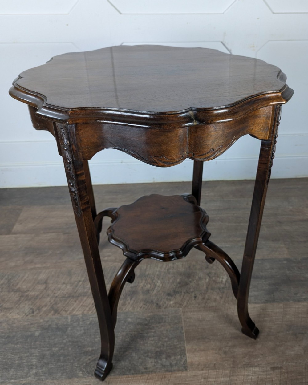 An early 20th-century walnut side table featuring a scalloped rim, carved legs, and a lower undertier shelf. View VII
