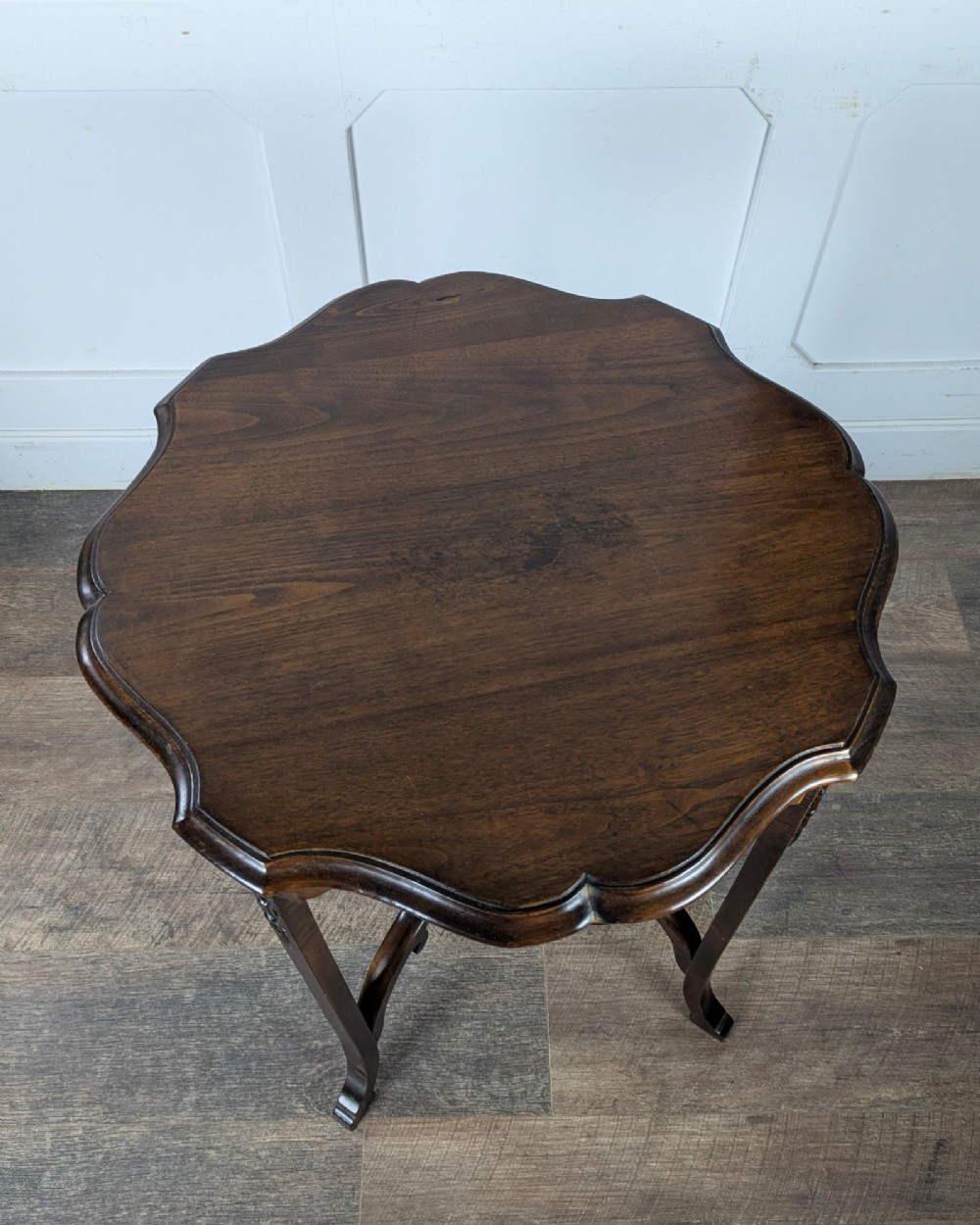 An early 20th-century walnut side table featuring a scalloped rim, carved legs, and a lower undertier shelf. View VIII
