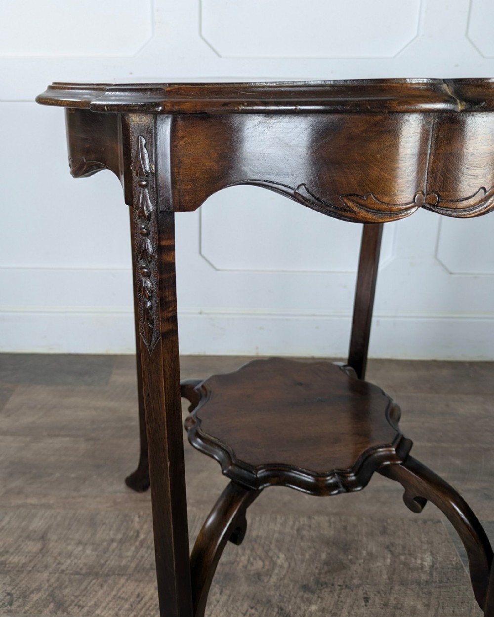 An early 20th-century walnut side table featuring a scalloped rim, carved legs, and a lower undertier shelf. View IX