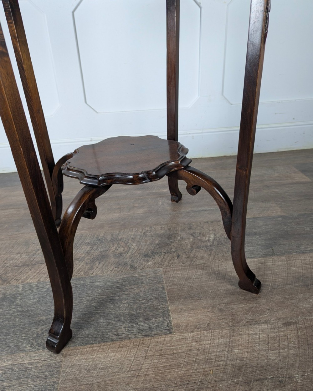 An early 20th-century walnut side table featuring a scalloped rim, carved legs, and a lower undertier shelf. View X