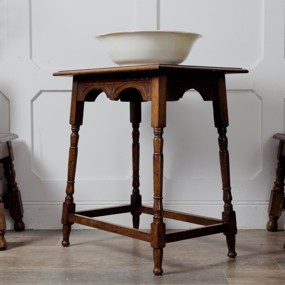 A late Victorian solid oak side table featuring carved apron arches, turned legs, and a rectangular top supported by low box stretchers.