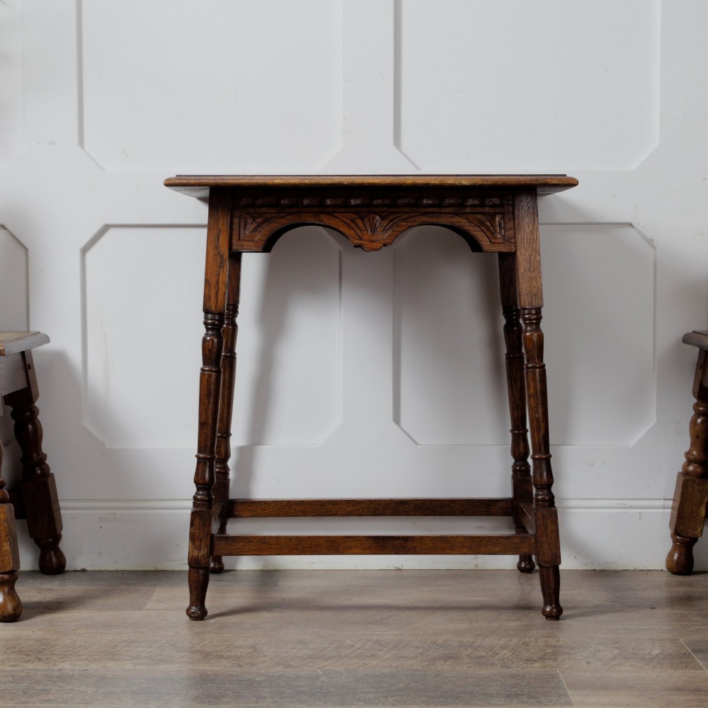A late Victorian solid oak side table featuring carved apron arches, turned legs, and a rectangular top supported by low box stretchers. View V