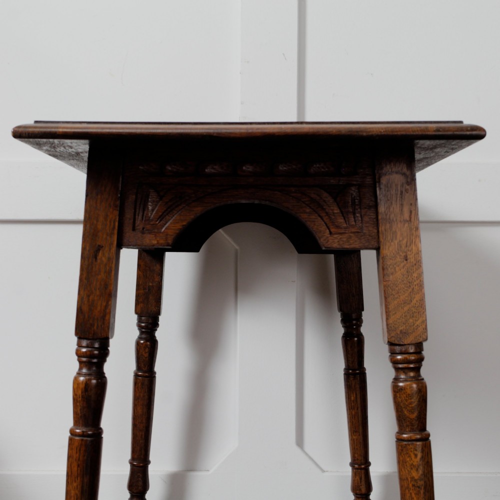 A late Victorian solid oak side table featuring carved apron arches, turned legs, and a rectangular top supported by low box stretchers. View VI