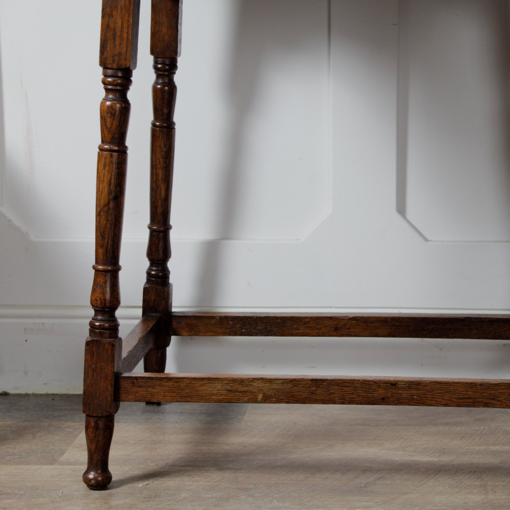 A late Victorian solid oak side table featuring carved apron arches, turned legs, and a rectangular top supported by low box stretchers. View XII