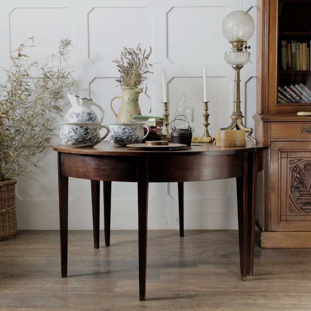 A pair of Georgian walnut demilune tables placed together to form a single round top with tapered legs. View II