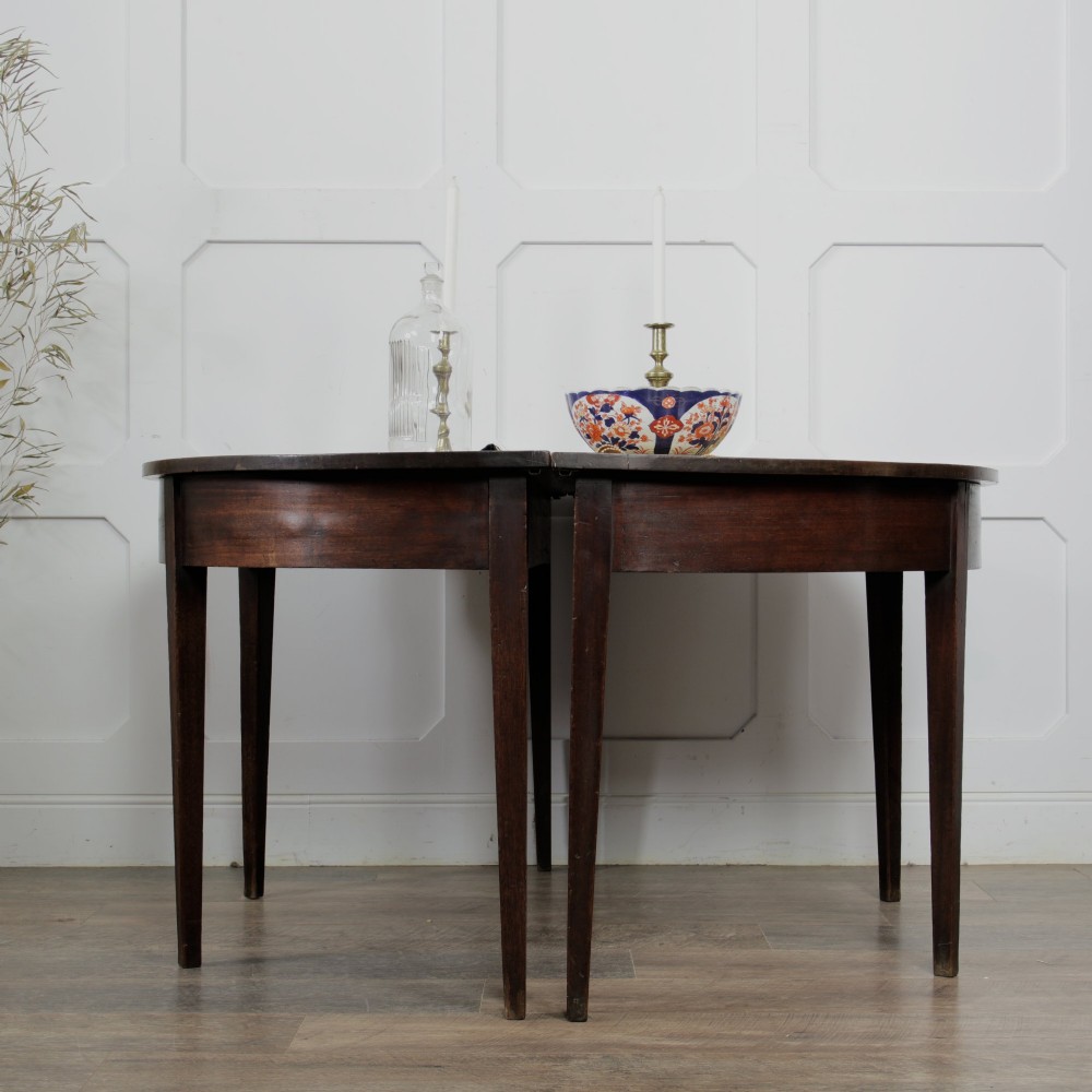 A pair of Georgian walnut demilune tables placed together to form a single round top with tapered legs. View IV