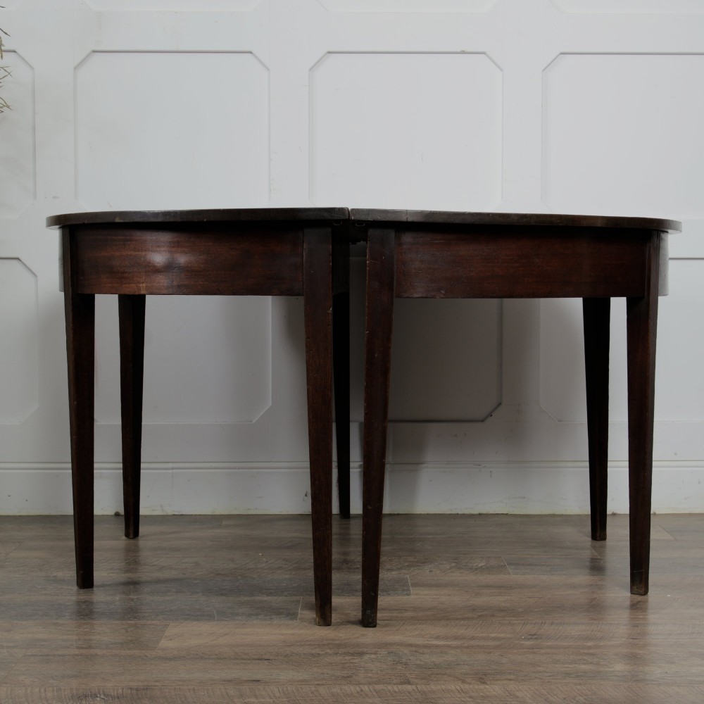A pair of Georgian walnut demilune tables placed together to form a single round top with tapered legs. View VI