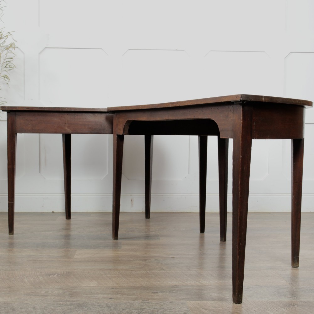 A pair of Georgian walnut demilune tables placed together to form a single round top with tapered legs. View VII