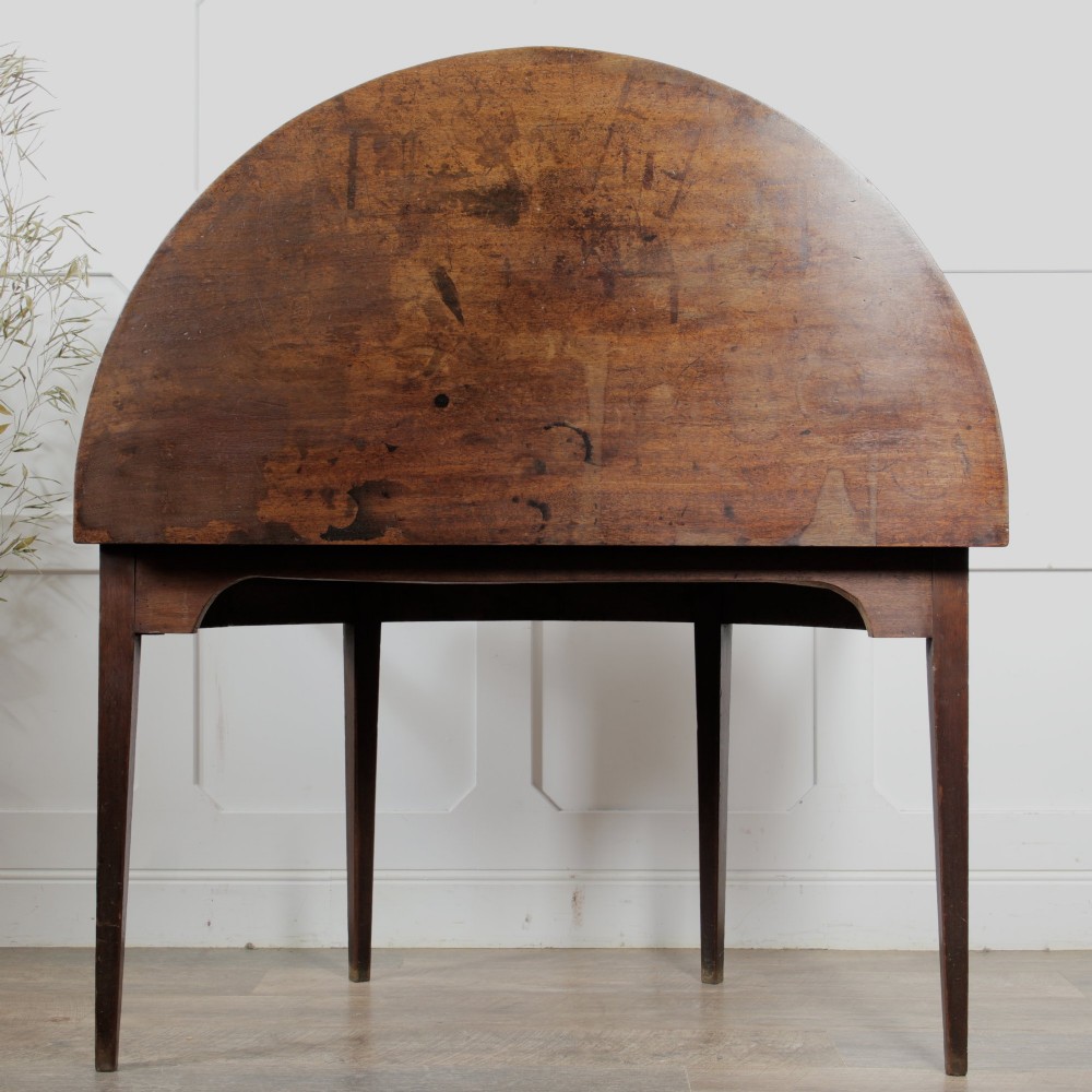 A pair of Georgian walnut demilune tables placed together to form a single round top with tapered legs. View X