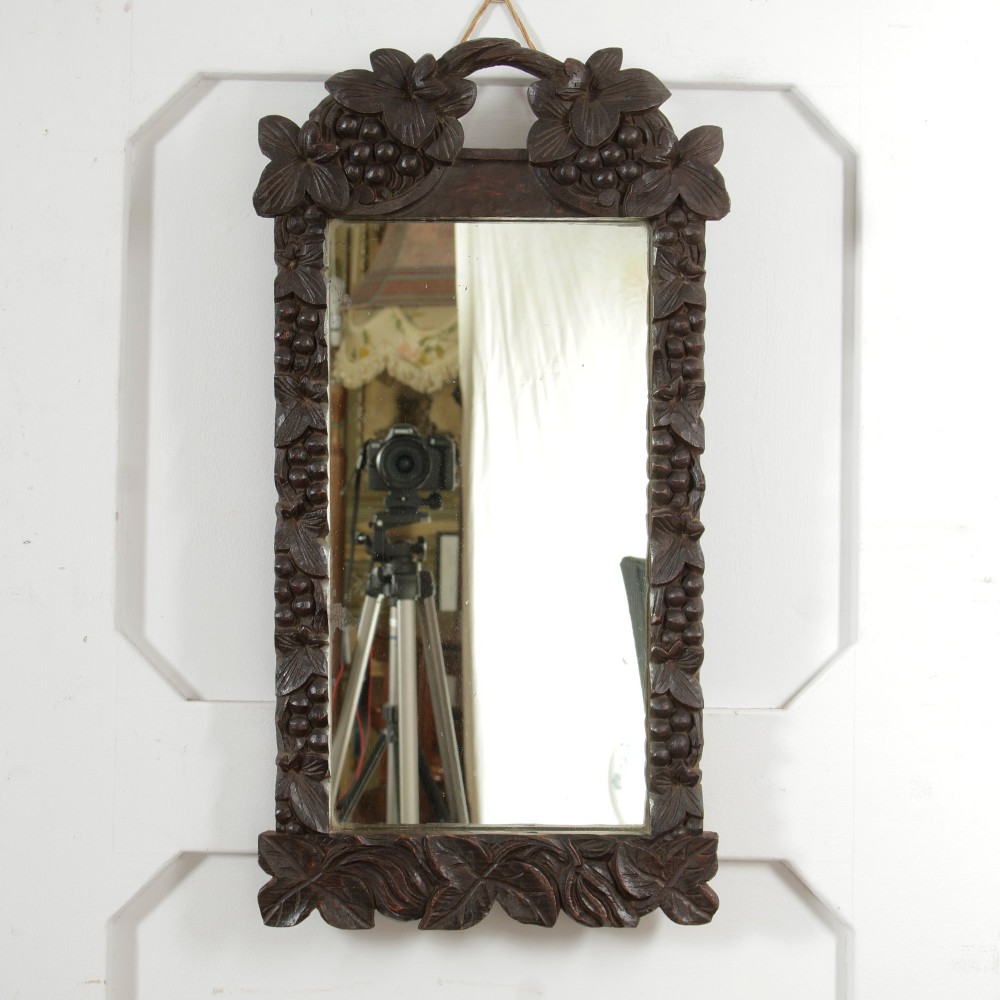 A rectangular nineteenth-century dark oak wall mirror featuring hand-carved leaf and grape motifs around the wooden frame. View II