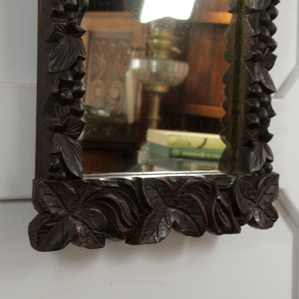 A rectangular nineteenth-century dark oak wall mirror featuring hand-carved leaf and grape motifs around the wooden frame. View V