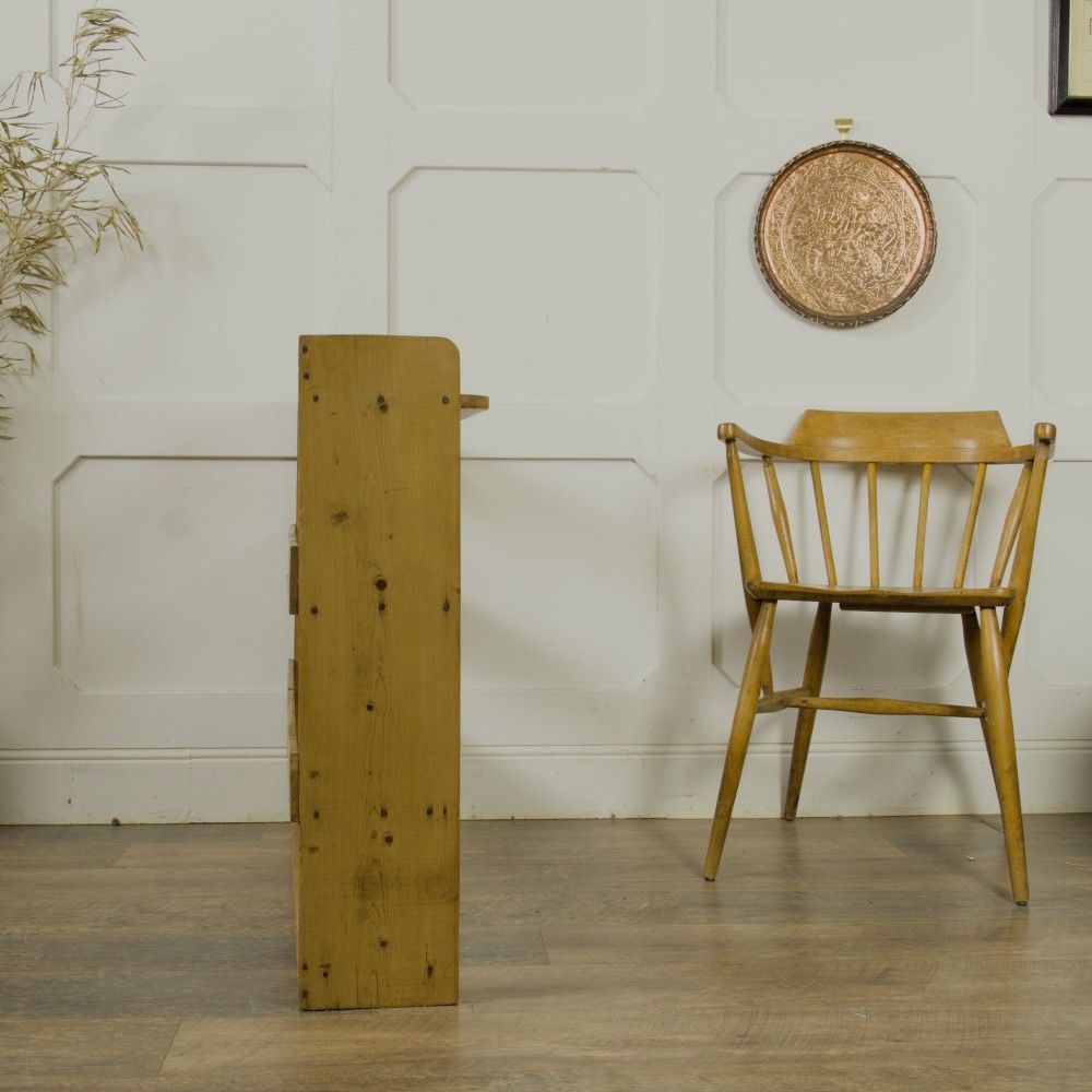 A low three-tier vintage pine open-backed bookshelf with natural timber grain and knots visible throughout. View VII