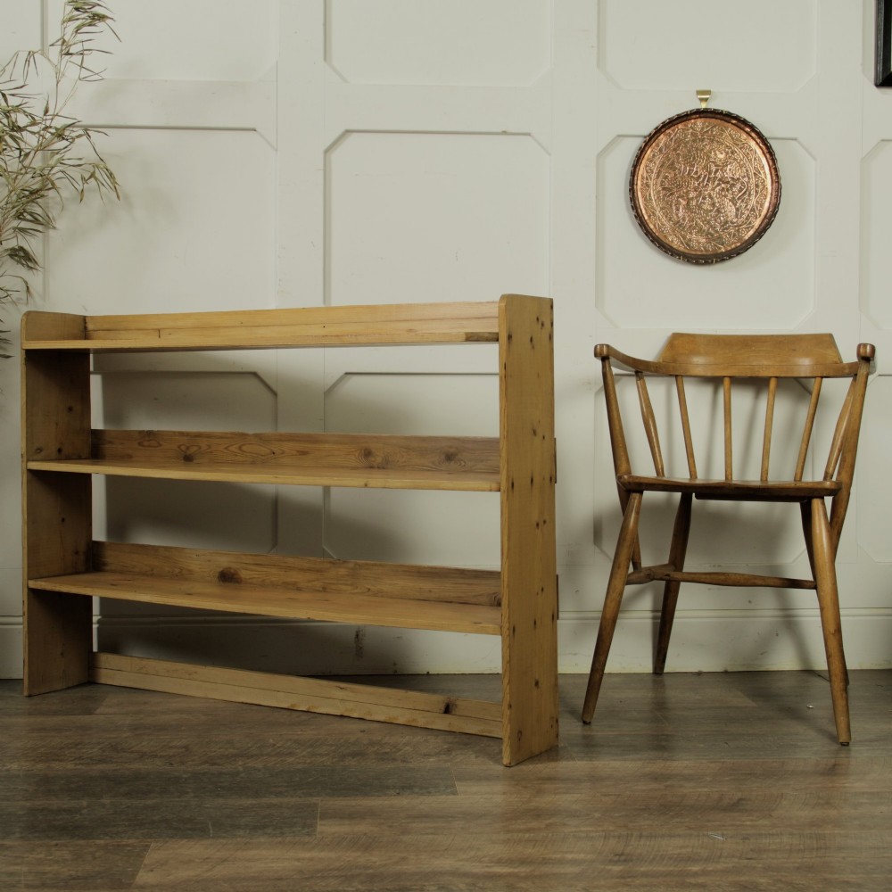 A low three-tier vintage pine open-backed bookshelf with natural timber grain and knots visible throughout. View IX