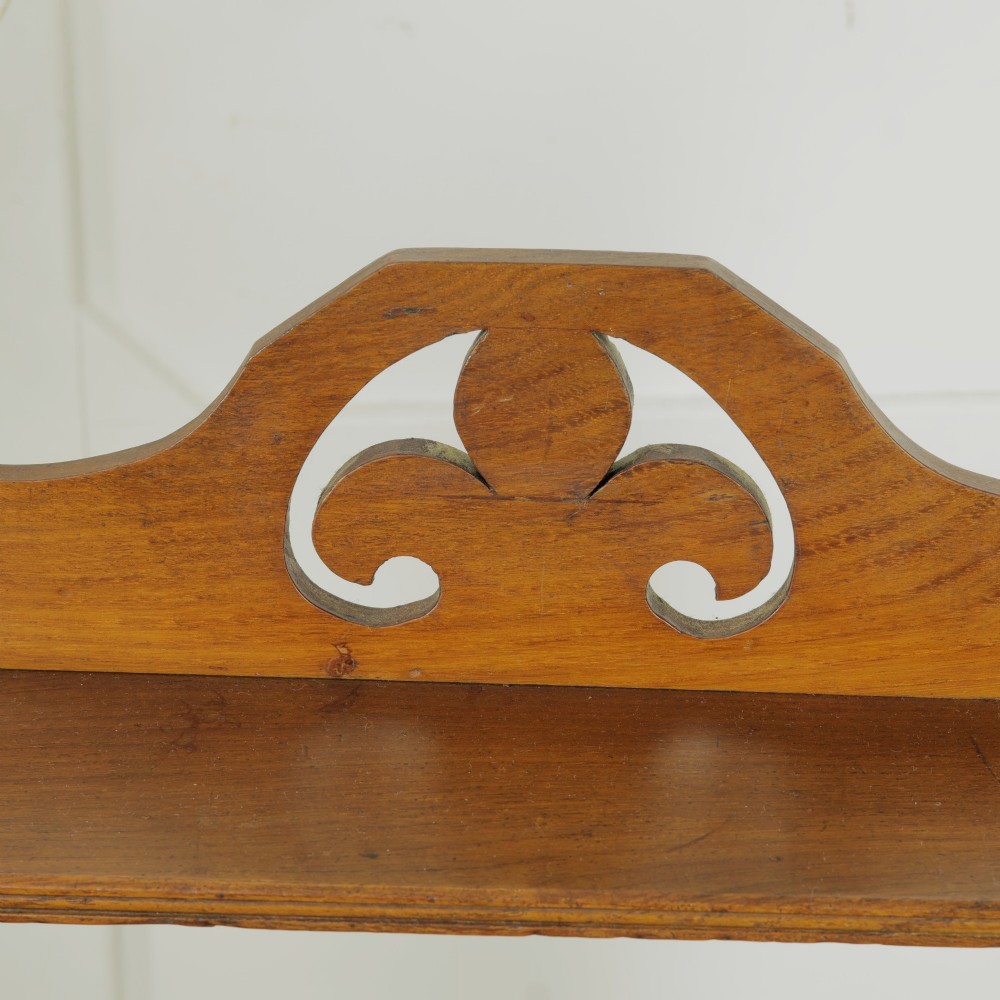 A three-tier warm brown wooden wall shelving unit featuring shaped side supports, wedged tenons, and a carved pierced cresting pediment. View VI