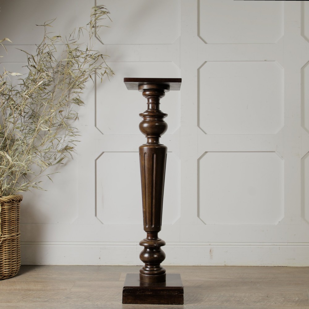 A dark turned mahogany plinth stand featuring a square top and base with a fluted central column. View VII