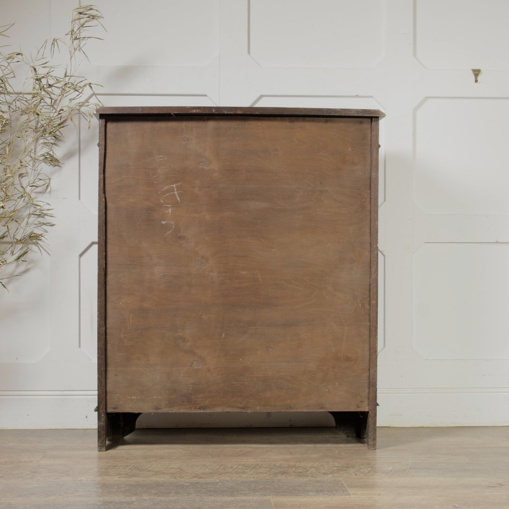 An early 20th-century dark oak open bookcase featuring a carved lunette frieze and three tiers of shelving. View V