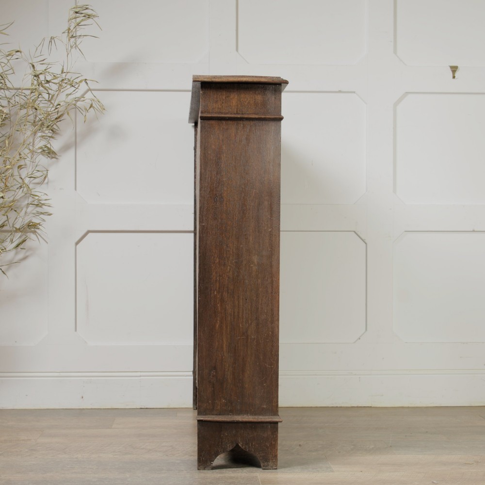 An early 20th-century dark oak open bookcase featuring a carved lunette frieze and three tiers of shelving. View VI