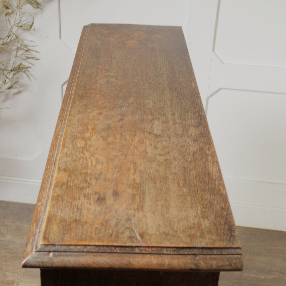 An early 20th-century dark oak open bookcase featuring a carved lunette frieze and three tiers of shelving. View VII