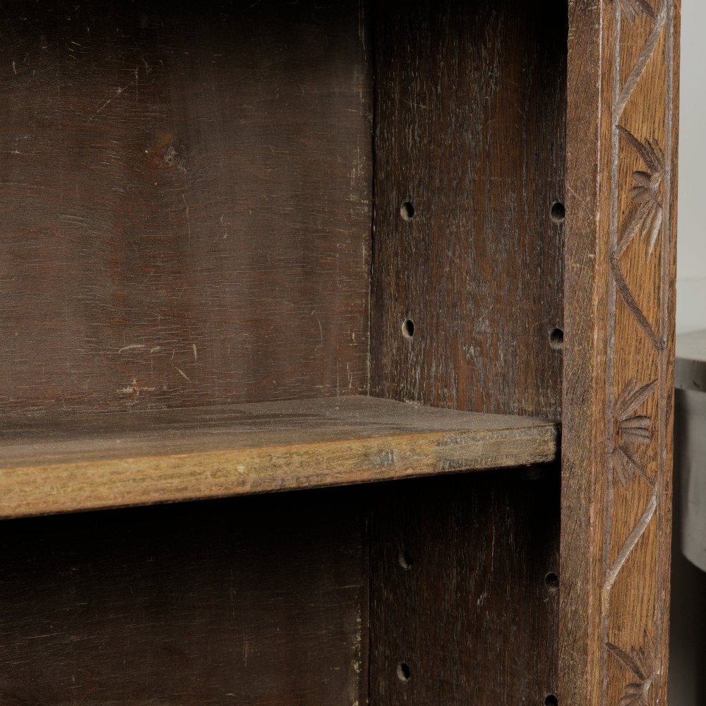 An early 20th-century dark oak open bookcase featuring a carved lunette frieze and three tiers of shelving. View XIII
