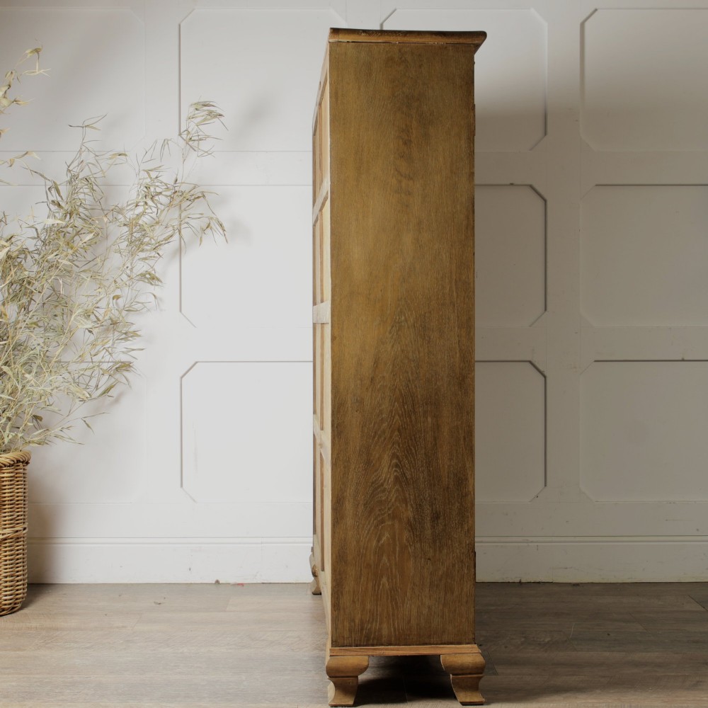 An early twentieth-century mellow oak glazed bookcase featuring twin glass-fronted doors over a lower cupboard with diagonal grain panels. View VI
