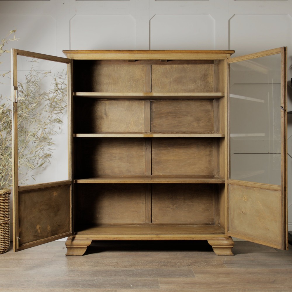 An early twentieth-century mellow oak glazed bookcase featuring twin glass-fronted doors over a lower cupboard with diagonal grain panels. View VII