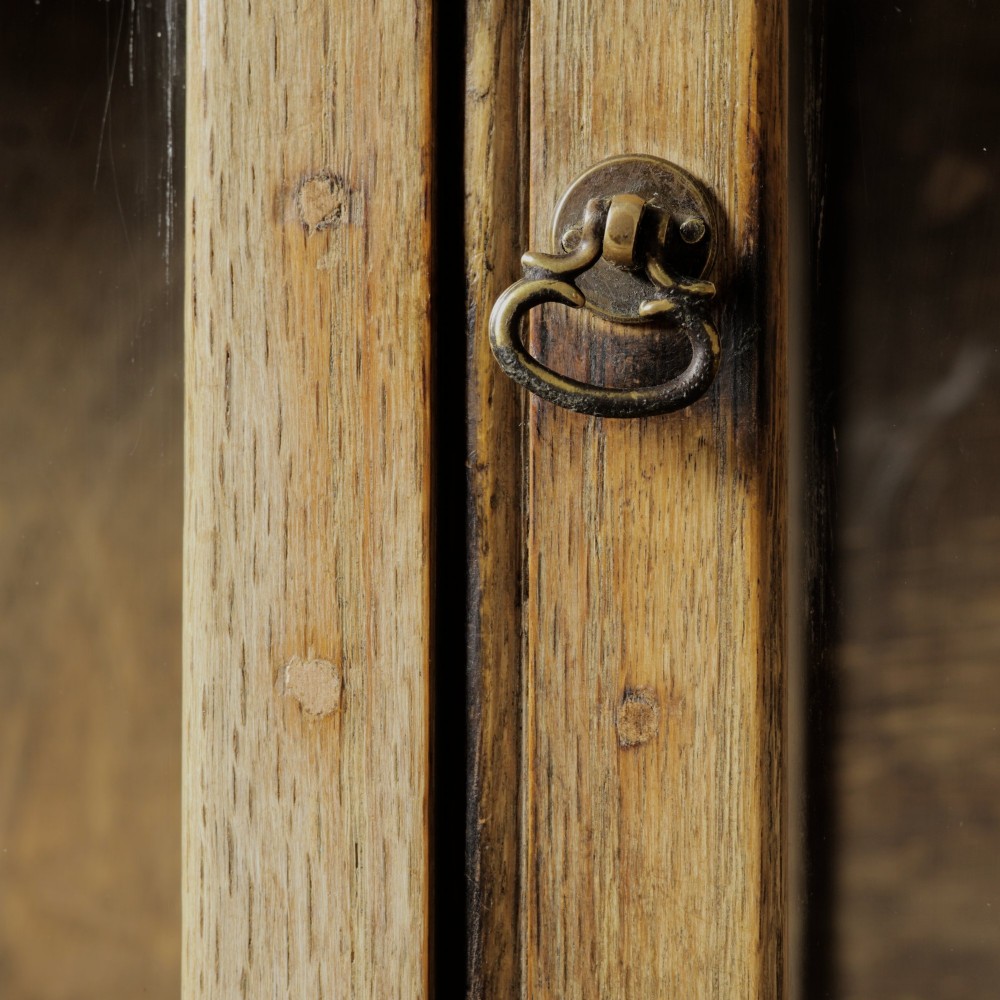 An early twentieth-century mellow oak glazed bookcase featuring twin glass-fronted doors over a lower cupboard with diagonal grain panels. View IX