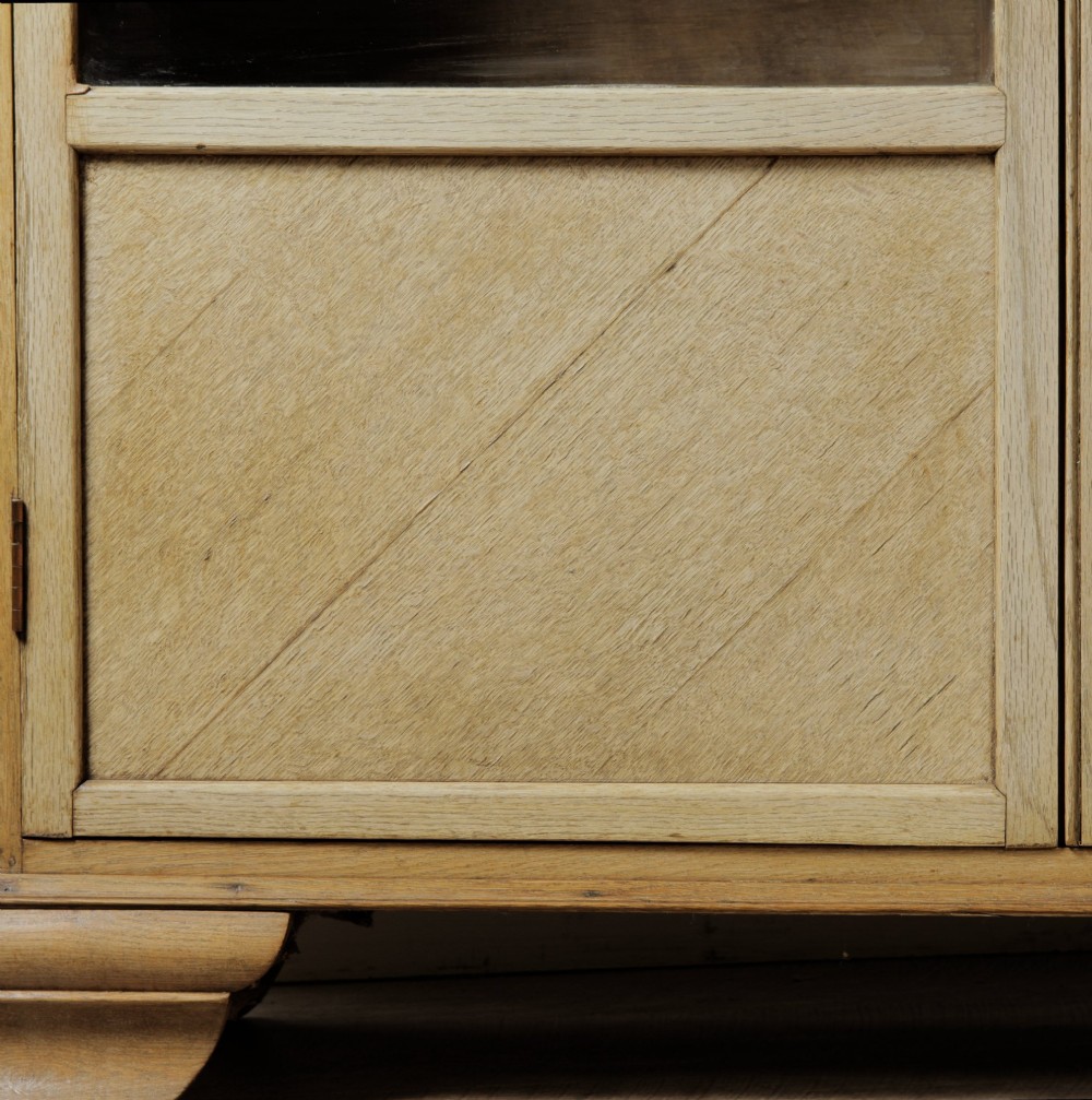 An early twentieth-century mellow oak glazed bookcase featuring twin glass-fronted doors over a lower cupboard with diagonal grain panels. View X