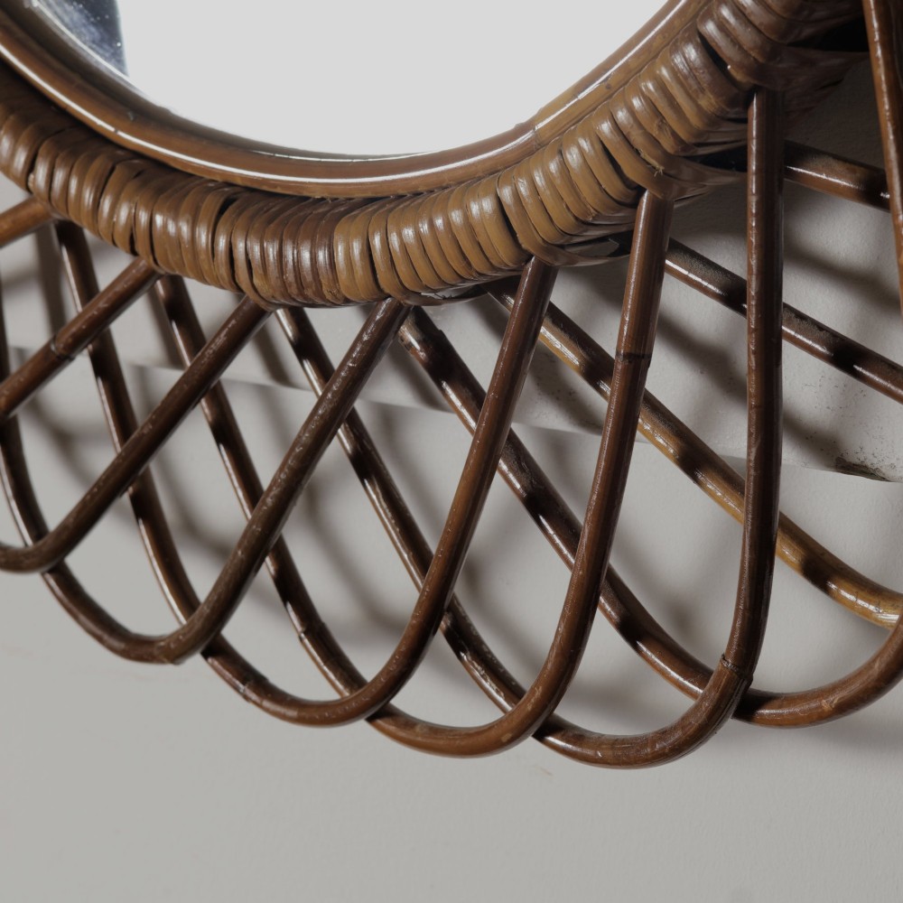 An oval mid-century wall mirror with an openwork outer frame crafted from woven, looped honey-toned rattan. View II