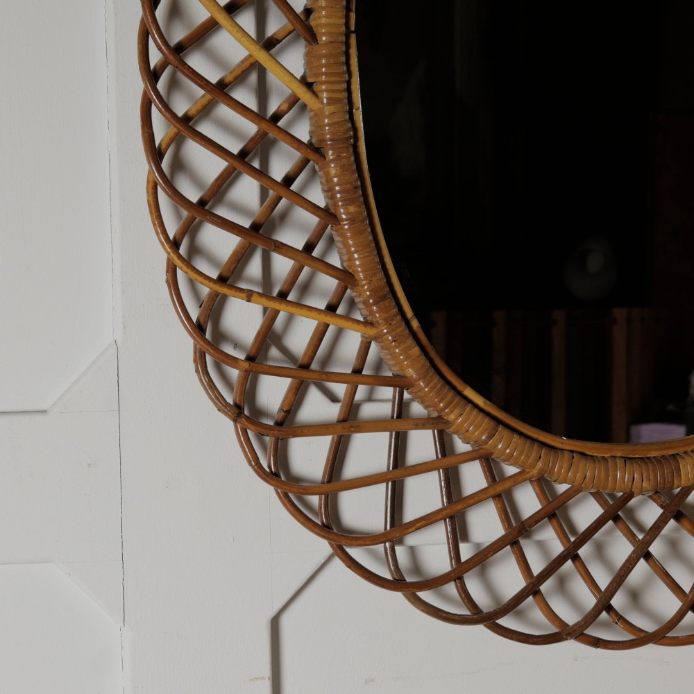 An oval mid-century wall mirror with an openwork outer frame crafted from woven, looped honey-toned rattan. View VII