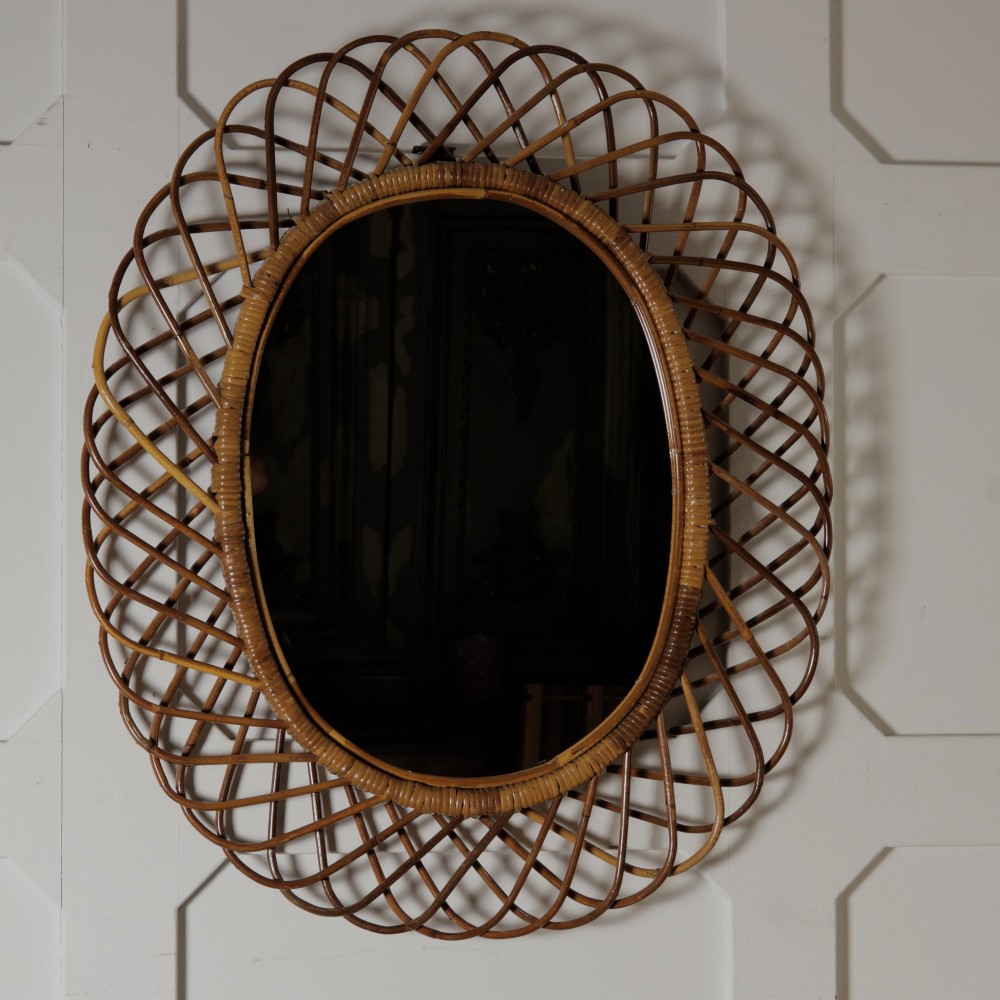 An oval mid-century wall mirror with an openwork outer frame crafted from woven, looped honey-toned rattan. View VIII