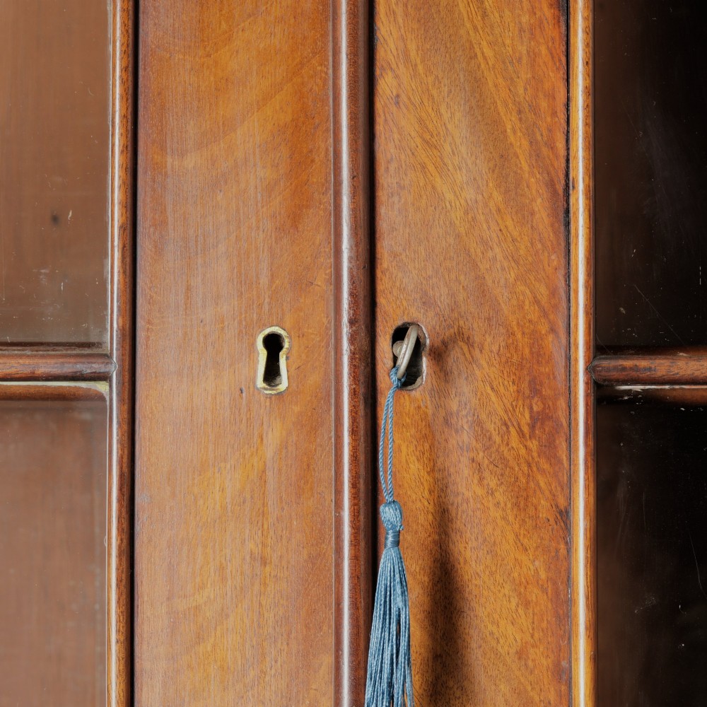 A two-tier Victorian mahogany chiffonier bookcase with arched glass double doors on the upper section and panelled cupboard doors on the lower base. View IV