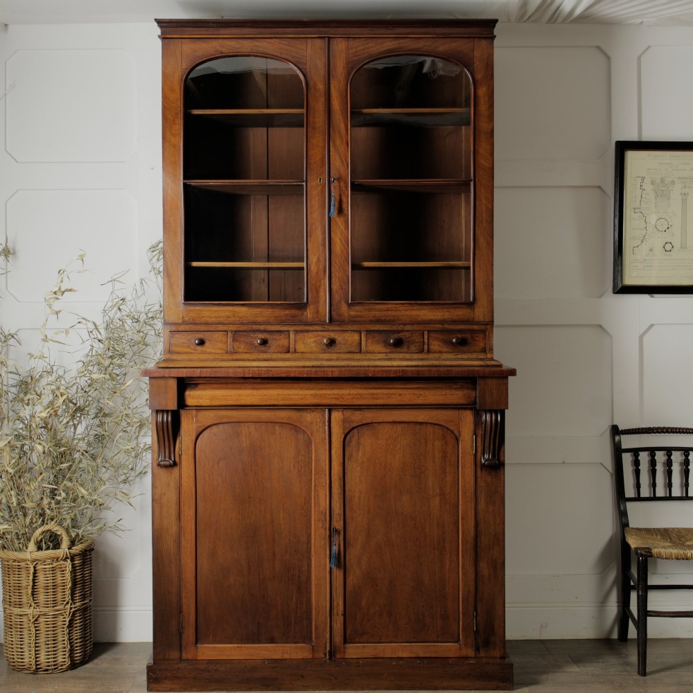 A two-tier Victorian mahogany chiffonier bookcase with arched glass double doors on the upper section and panelled cupboard doors on the lower base. View XI