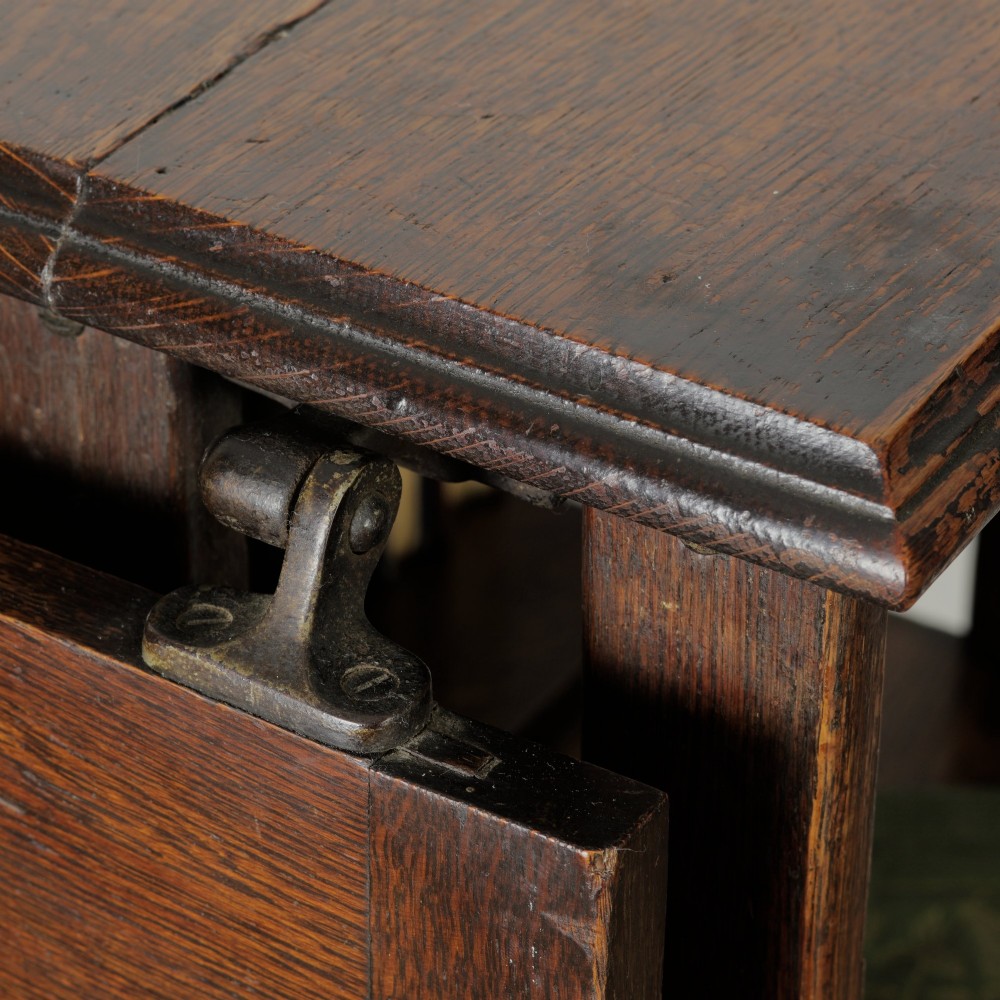 An Edwardian dark oak revolving bookcase featuring vertical slats, multiple shelf tiers, an adjustable folding reading rest, and a quadruped base on castors. View XIII