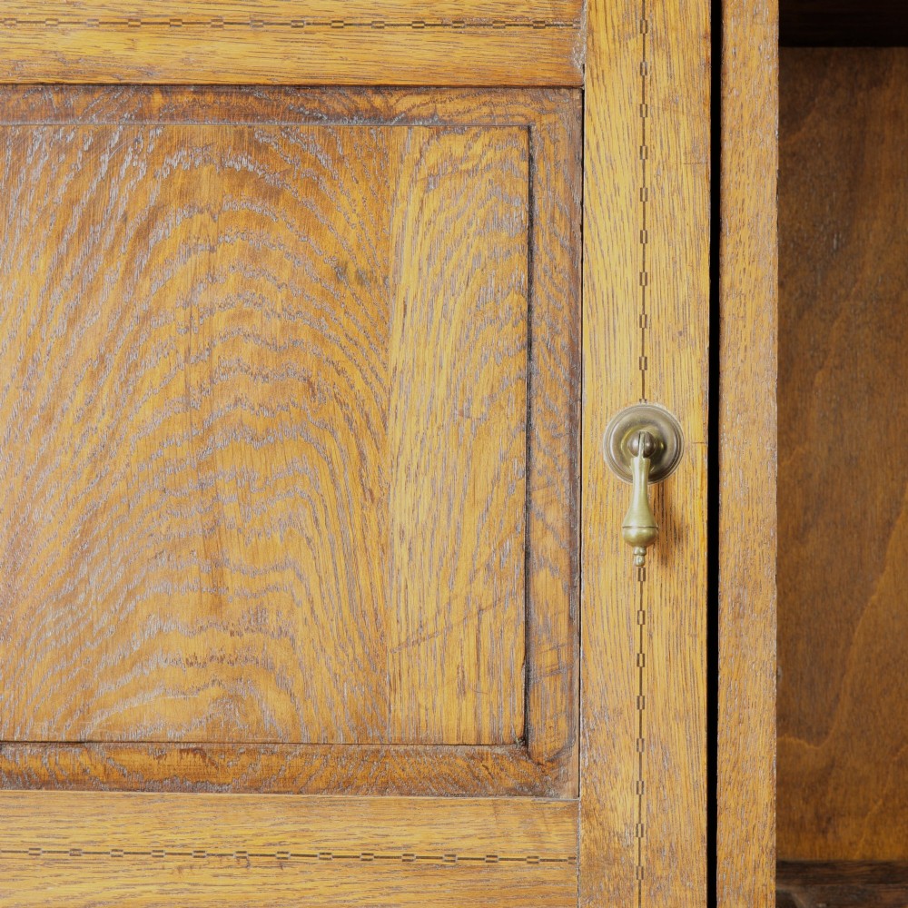 A solid honey-coloured oak dresser featuring a top section with open shelving and small side cupboards, set upon a base with six drawers and brass swan-neck handles. View III