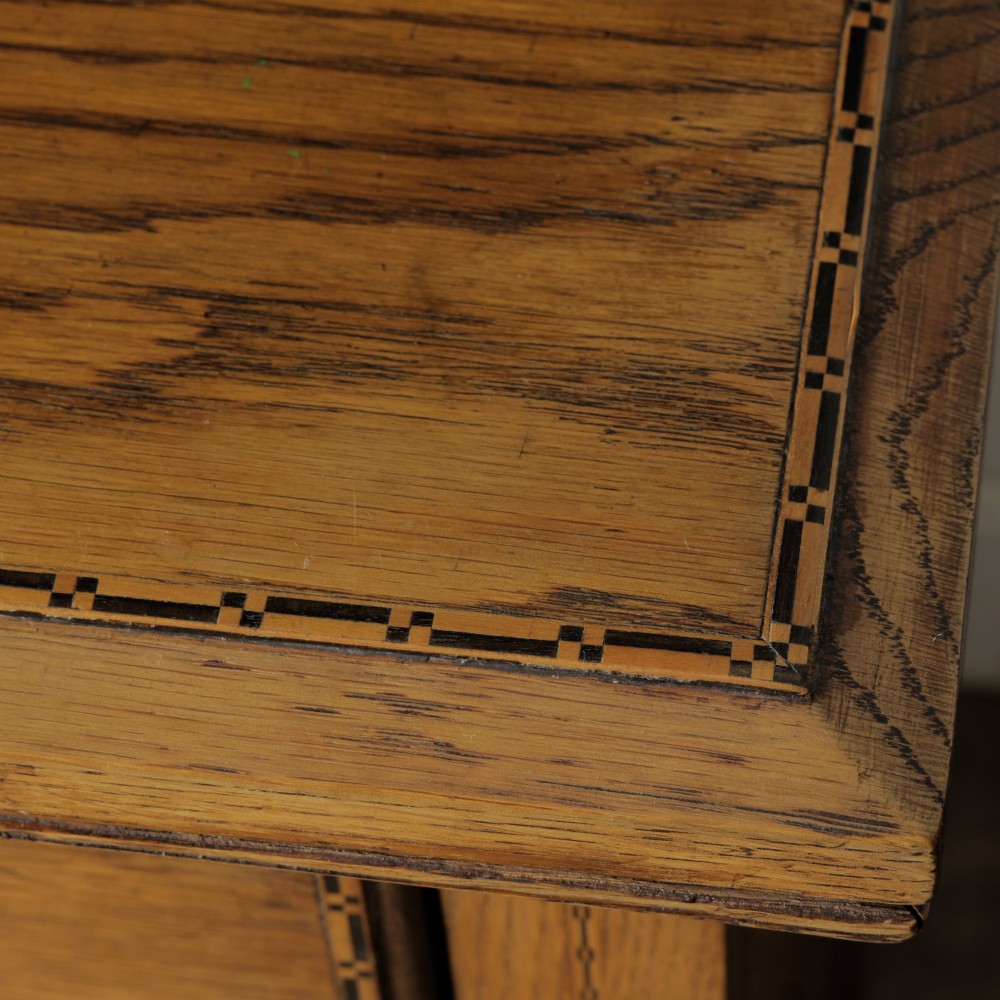 A solid honey-coloured oak dresser featuring a top section with open shelving and small side cupboards, set upon a base with six drawers and brass swan-neck handles. View V