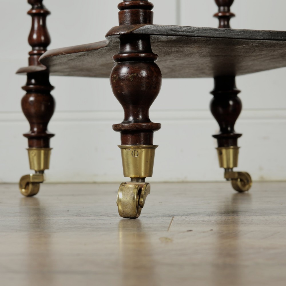 A dark wood Victorian two-tier whatnot featuring hand-turned barley twist legs, top corner finials, and brass casters. View VI