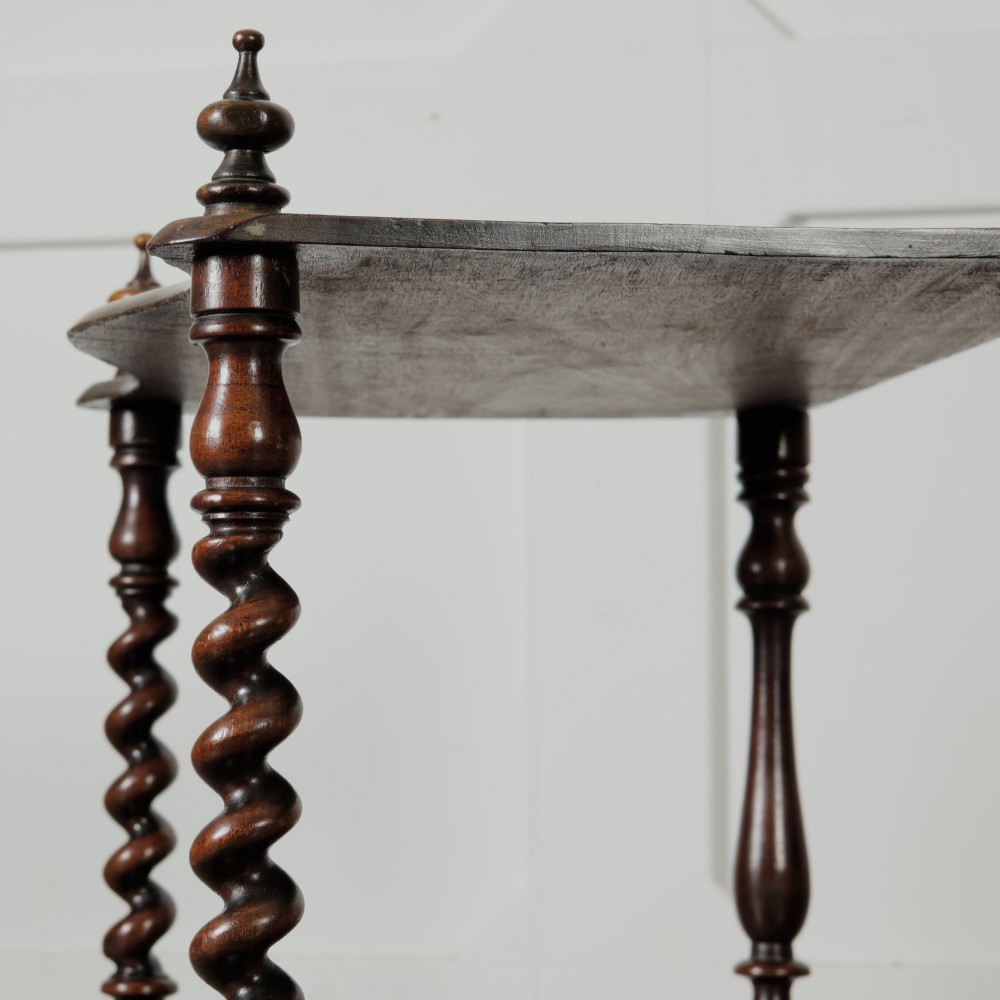 A dark wood Victorian two-tier whatnot featuring hand-turned barley twist legs, top corner finials, and brass casters. View VII
