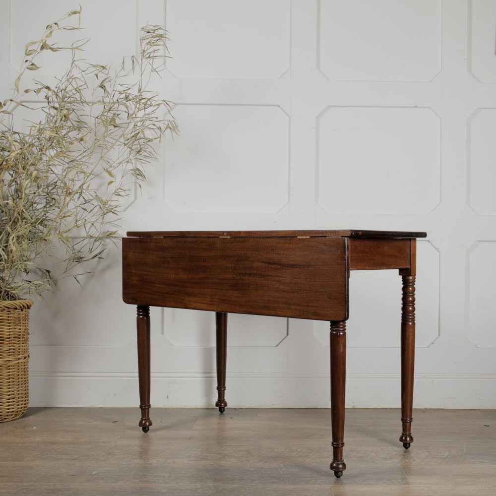 A Victorian mahogany drop-leaf table featuring a single hinged flap, turned legs, and small wheel castors.