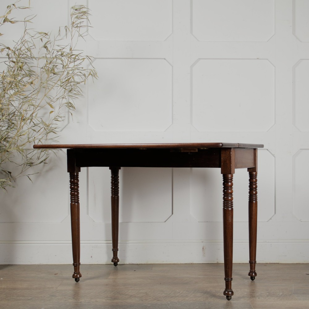 A Victorian mahogany drop-leaf table featuring a single hinged flap, turned legs, and small wheel castors. View V