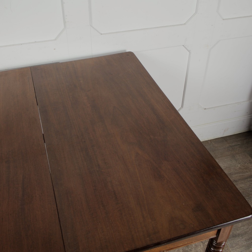 A Victorian mahogany drop-leaf table featuring a single hinged flap, turned legs, and small wheel castors. View VI