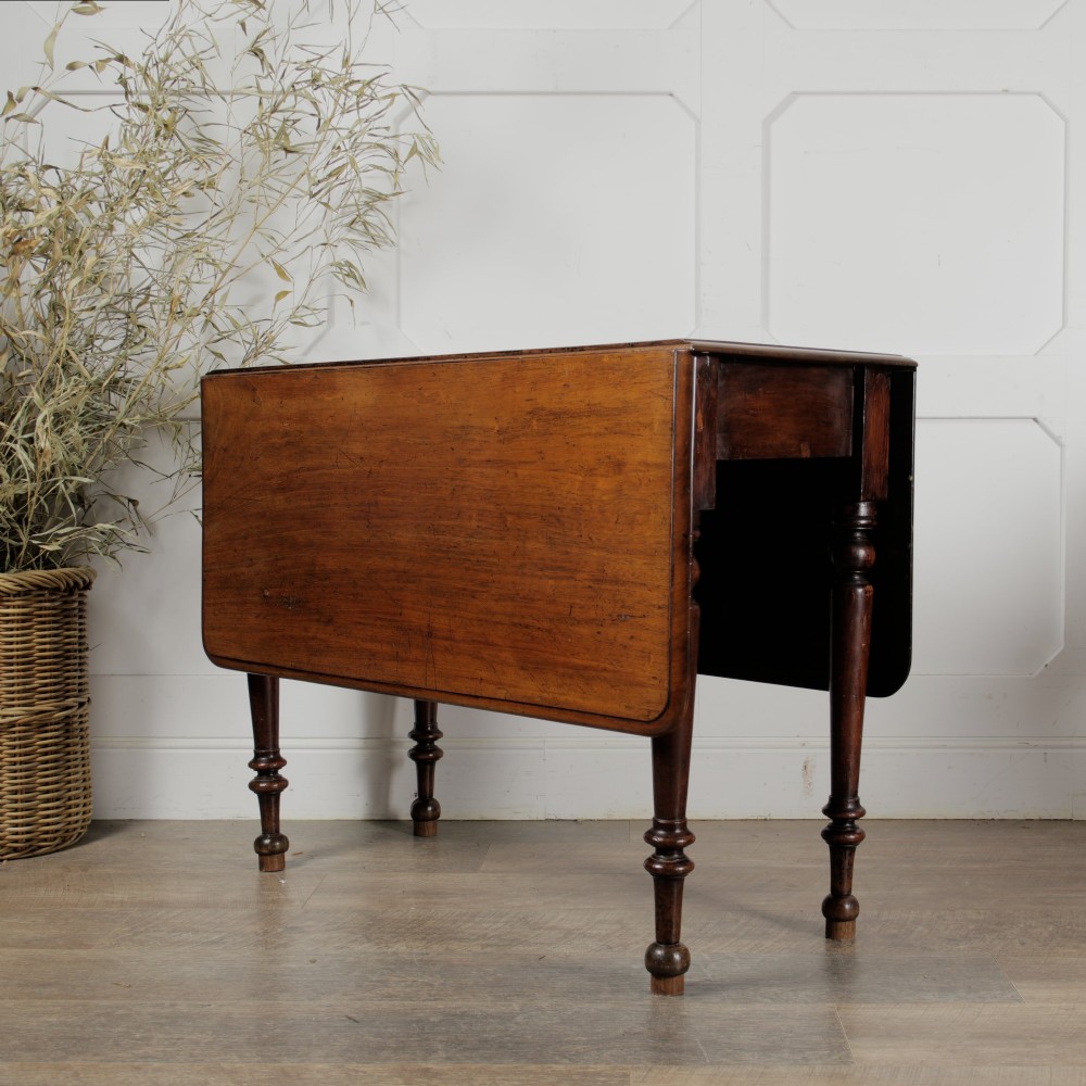 A Victorian mahogany gateleg table with two hinged drop leaves, a rectangular top, and turned wooden legs.