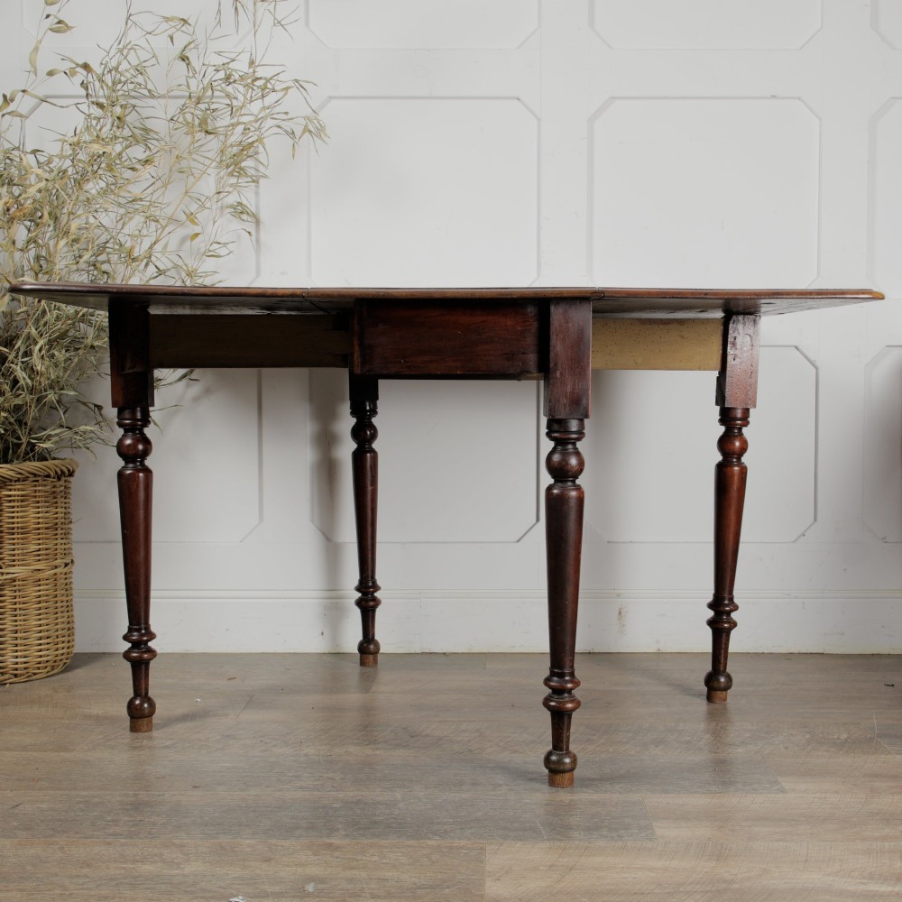 A Victorian mahogany gateleg table with two hinged drop leaves, a rectangular top, and turned wooden legs. View V
