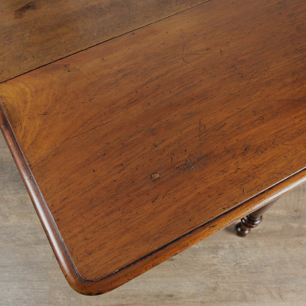 A Victorian mahogany gateleg table with two hinged drop leaves, a rectangular top, and turned wooden legs. View VII