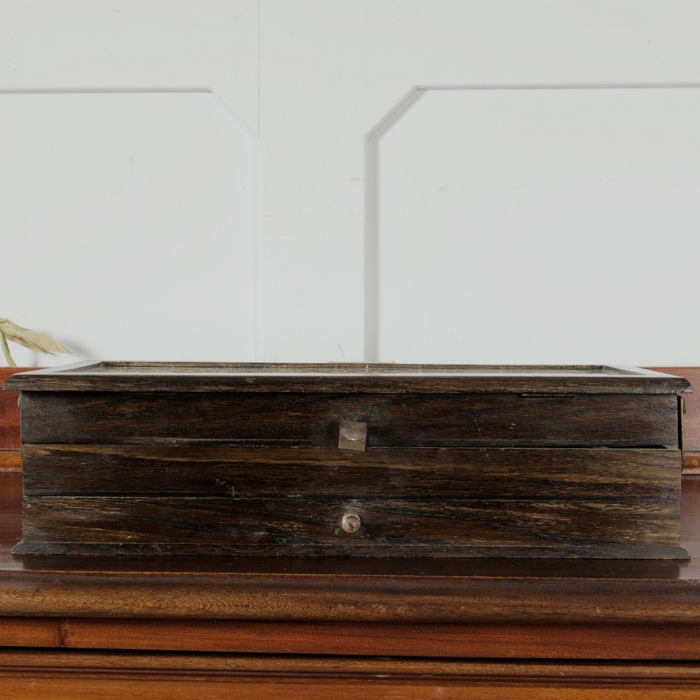 A dark wooden multi-tiered cantilever haberdashery display box with a glass lid bearing a yellow anchor logo, shown open with thread spools inside. View XII